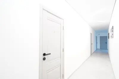 an empty corridor with a white door in a white hallway at Svaja ApartHotel & SPA in Šiauliai