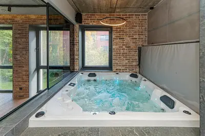 a large hot tub in a room with windows at Design 2 BD Apartment with Hot Tube by Domvia in Kaunas