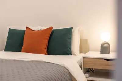 a bed with orange and green pillows and a night stand at Old Town Retreat in Vilnius in Vilnius