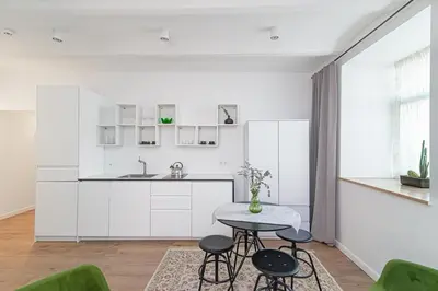 a kitchen with white cabinets and a table and chairs at Gate of Dawn Old town in Vilnius