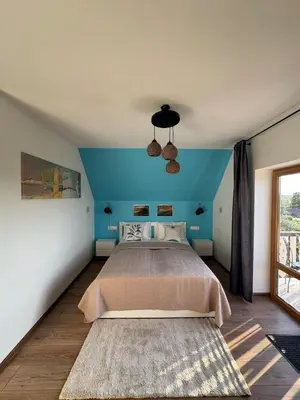 a bedroom with a large bed with a blue wall at Piliakalnio Apartmentai in Kupiškis