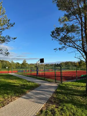 a tennis court with a fence and a basketball hoop at Piliakalnio Apartmentai in Kupiškis