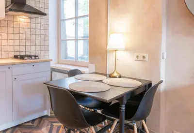 a table in a kitchen with four chairs and a lamp at Cozy Urban Apartment in Vilnius