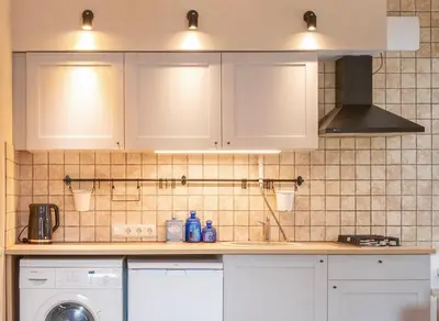 a kitchen with white cabinets and a washing machine at Cozy Urban Apartment in Vilnius