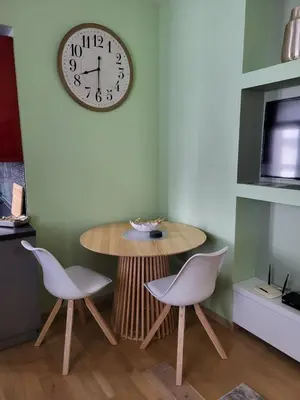 a table and two chairs and a clock on a wall at Siauliai Apartments - Traku in Šiauliai