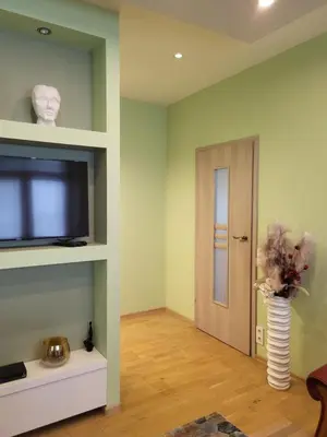 a living room with a flat screen tv and a door at Siauliai Apartments - Traku in Šiauliai