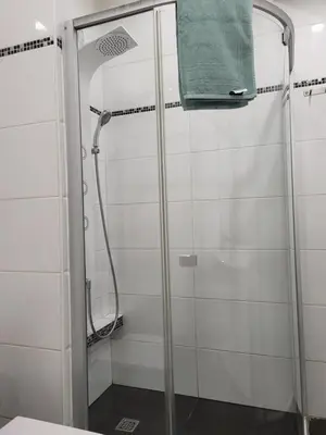 a shower stall with a green towel hanging on it at Siauliai Apartments - Traku in Šiauliai