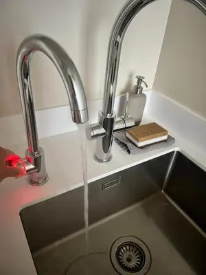 a kitchen sink with water running from two faucets at Designer studio in Vilnius