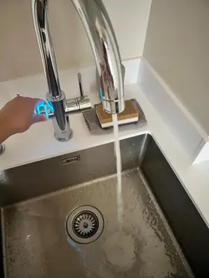 a kitchen sink with water running from a faucet at Designer studio in Vilnius