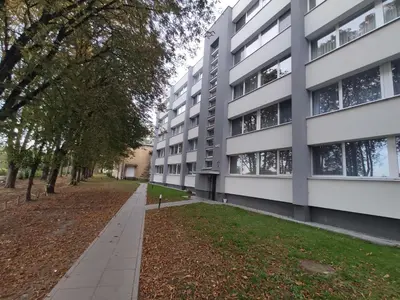 an apartment building with a sidewalk and trees at Rasa in Marijampolė