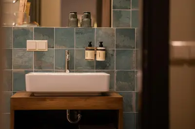 a bathroom sink with two bottles on a tiled wall at Pievos in Birštonas
