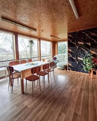 a dining room with a table and chairs and a stone wall at Sodyba prie Mūšos