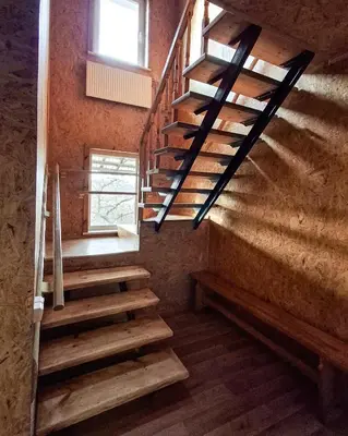 a set of wooden stairs in a room with a window at Sodyba prie Mūšos