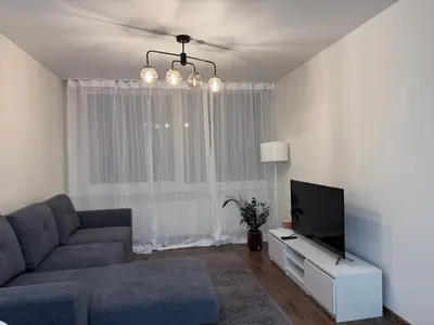 a living room with a couch and a tv at EVA apartment in Marijampolė
