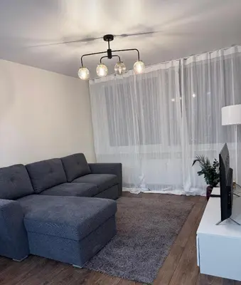 a living room with a blue couch in front of a window at EVA apartment in Marijampolė