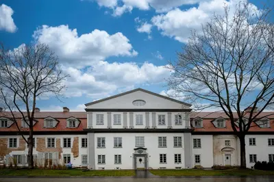 a large white building with trees in the foreground at Luxury apartment in Old Town and Parking in Vilnius