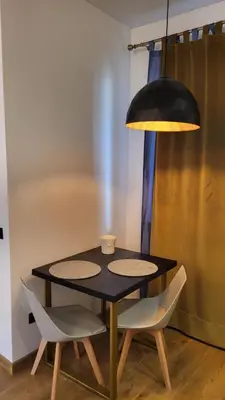 a black table with two white chairs and a lamp at Old town studio in Kaunas