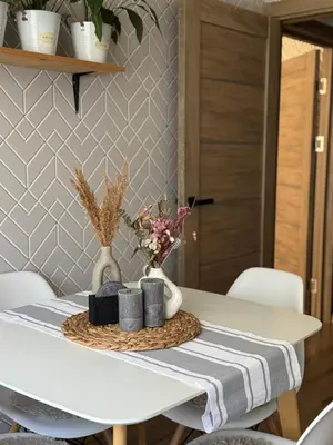 a white dining table with a white vase and flowers at Feels like home in Visaginas