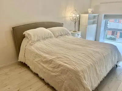 a bedroom with a bed with a white comforter and a window at Kaunas Design Loft in Kaunas