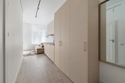 a hallway of a kitchen with white cabinets and a mirror at Šopeno Butas Comfort & Relax in Old Town 2 in Vilnius