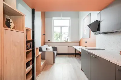 a kitchen and living room with an orange wall at Vytenio Loft - Serenity and Style in City Centre 23 in Vilnius
