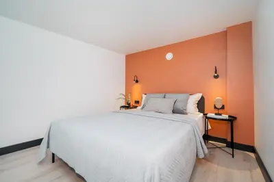a bedroom with a white bed and an orange wall at Vytenio Loft - Serenity and Style in City Centre 23 in Vilnius