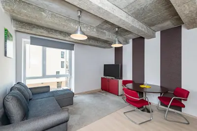 a living room with a couch and a table and red chairs at Apartment Accent by Polo Apartments in Kaunas