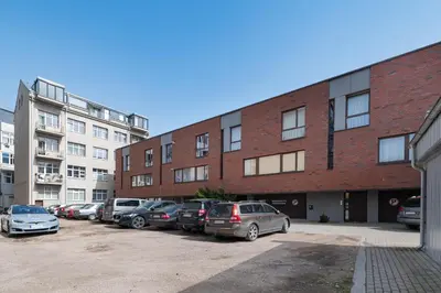 a parking lot with cars parked in front of a brick building at Apartment Accent by Polo Apartments in Kaunas