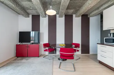 a kitchen with red chairs and a table with a tv at Apartment Accent by Polo Apartments in Kaunas
