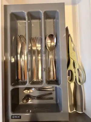 a drawer filled with silver utensils and scissors at Crown Apartment Park View in Ukmergė