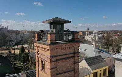 a brick tower with a balcony on top of a building at Crown Apartment Park View in Ukmergė