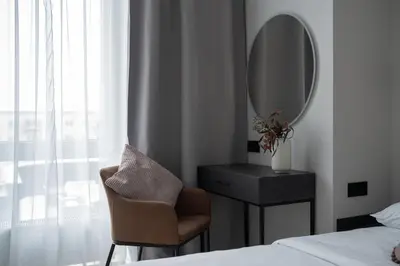 a bedroom with a bed and a mirror and a chair at Cozy 4 Two - City Center Apartment in Kaunas