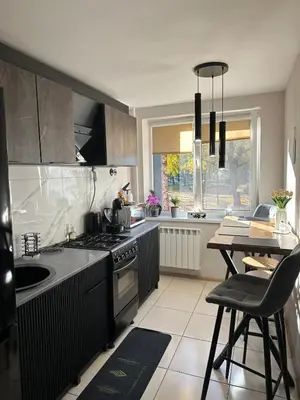 a kitchen with a stove and a table in it at Newly renovated cosy apartment near scenic river in Jonava