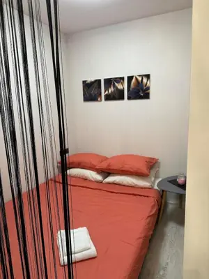 a room with a bed with red sheets and two pictures at Newly renovated cosy apartment near scenic river in Jonava