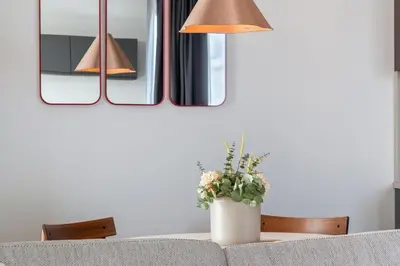 a table with two lamps and a vase with flowers at Terrace Apartment near Ozas in Vilnius