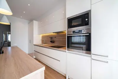 a kitchen with white cabinets and stainless steel appliances at Marijonų Apartamentai in Panevėžys