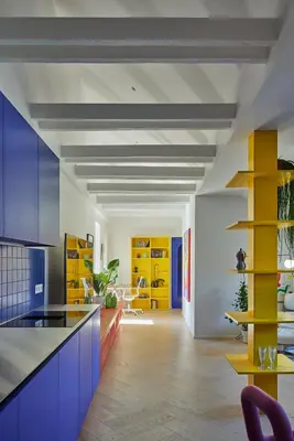 a kitchen with blue cabinets and yellow shelves at Pop Haus Vilnius in Vilnius