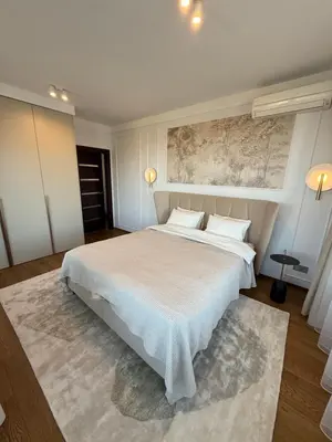 a bedroom with a large white bed with a rug at Luxury Oasis in the Heart of the City in Druskininkai