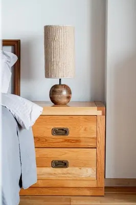 a wooden nightstand with a lamp on it next to a bed at Studio in central Vilnius in Vilnius