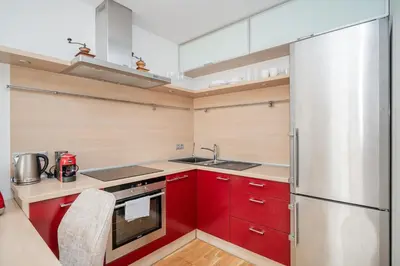 a kitchen with red cabinets and a stainless steel refrigerator at Studio in central Vilnius in Vilnius