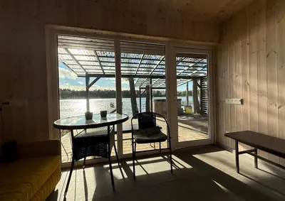 a room with a table and chairs and a view of the water at Peaceful lake retreat with sauna