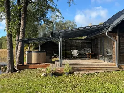 a log cabin with a deck and a table at Peaceful lake retreat with sauna