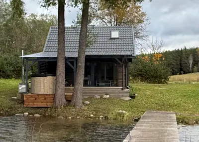 a cabin by the water with trees and a dock at Peaceful lake retreat with sauna