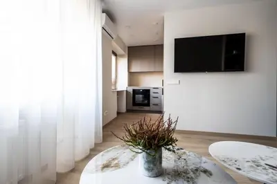 a living room with a table and a tv on a wall at Vytauto 12 - jaukūs apartamentai centre - Self Check-in in Marijampolė
