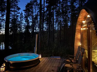 a jacuzzi tub on a deck in the woods at Lakajų Resort in Molėtai