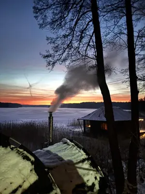 a house with smoke coming out of it at sunset at Lakajų Resort in Molėtai