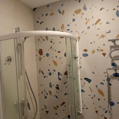 a bathroom with a shower and a wall covered in rocks at VilniusCentralSpot in Vilnius
