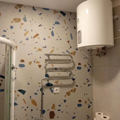 a bathroom with a wall covered in broken tiles at VilniusCentralSpot in Vilnius