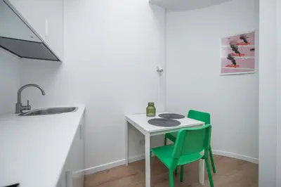 a kitchen with a white table and two green chairs at LUMA Apartments by Reside Baltic in Vilnius
