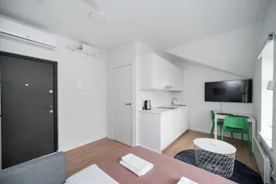 a room with a bed and a table and a kitchen at LUMA Apartments by Reside Baltic in Vilnius